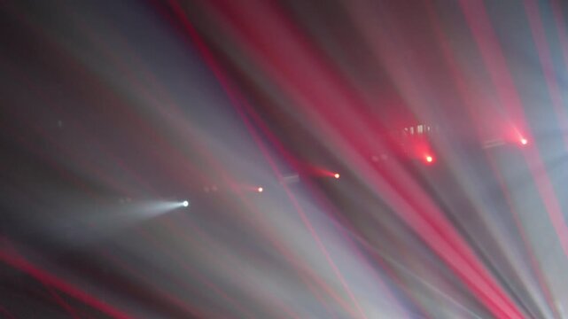 Strong stage lights and strobe effects spread across concert hall forming cinematic live music atmosphere without visible performers