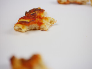 Single Slice of Pizza on White Surface with Shallow Depth of Field Highlighting Cheese Texture and Casual Food Presentation