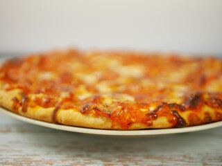 Whole Pizza Served on Plate Viewed from Low Angle Emphasizing Crust Thickness Toppings and Casual Home Dining Style