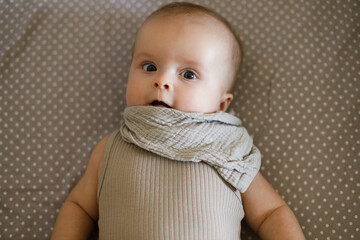 Cute happy baby lying in crib, close up. Sweet infant smiling portrait in grey bassinet, space for text. Childhood, Love and care concept. Time for sleep.