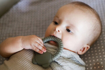 Cute baby lying in crib with  little teether, close up. Teething. Sweet infant portrait in bassinet with silicone toy. Childhood, Love and care concept.  Time for sleep.