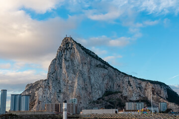 The massive limestone monolith of the Rock of Gibraltar towers above modern apartments and a wooden...