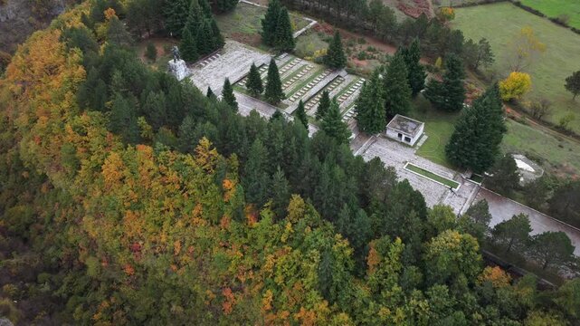 Aerial video of the Martyrs&rsquo; Cemetery of Bajram Curri surrounded by autumn forests and hillside greenery.