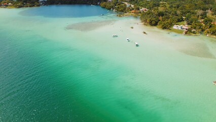 Boats anchored in shallow turquoise water near shore of Bacalar lagoon Mexico. © Olga Gorkun