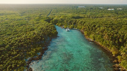 Catamaran anchored in turquoise lagoon by dense jungle in Grand Sirenis Mexico. © Olga Gorkun