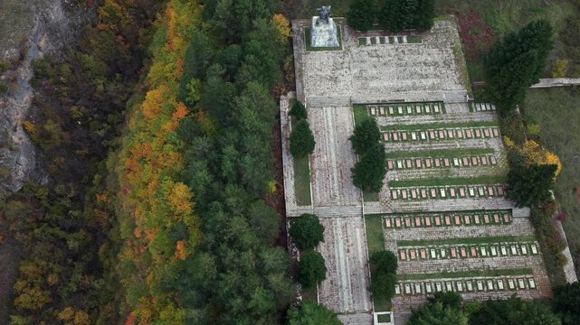 Top-down aerial video of the Martyrs&rsquo; Cemetery of Bajram Curri framed by autumn trees and memorial rows.