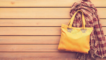 Yellow eco-friendly tote bag and scarf on a wooden background for hygge style
