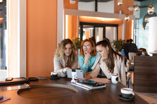 Businesswomen collaborating on mobile devices in a modern office environment during afternoon meeting hours - Powered by Adobe