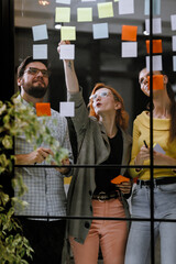 Team brainstorming session with colorful sticky notes on a glass wall in a modern office setting