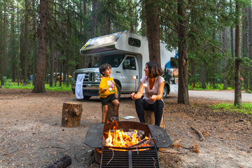 Family roasting marshmallows at campfire near camper van in banff national park