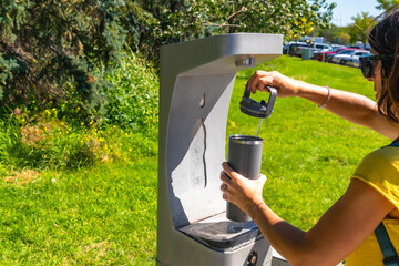 Tourist filling water bottle at public drinking water fountain in calgary