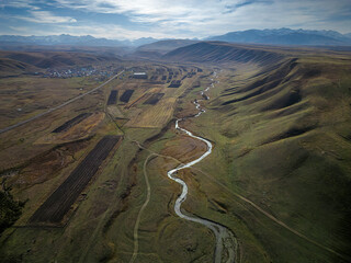 a mountain gorge with a river and fields