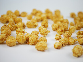 Side view of a pile of caramel popcorn balls on white table with soft blur, sweet crunchy snack concept for cinema food, branding and clean background