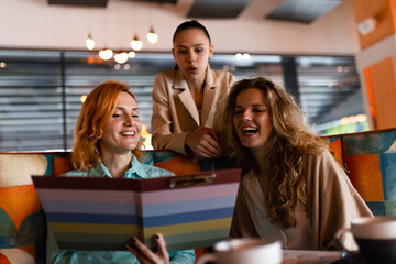 Businesswoman engaged in discussion with colleagues while reviewing a menu in a modern cafe during a morning meeting