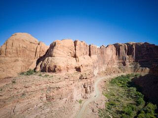 Fototapeta premium Dirt road leading up a canyon in Utah with a river bright day