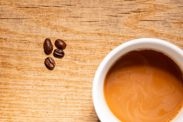Top down shot of a cup of coffee with whole beans on orange background food concept