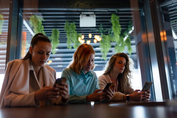 Businesswomen engaged in digital communication at a modern cafe during a networking event on a...