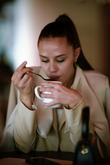 Young woman drinking soup with a spoon at a restaurant during lunch break
