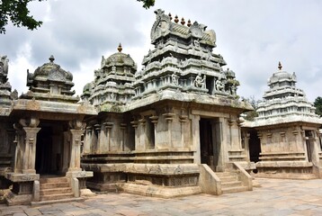 Ancient stone temple complex with intricate carvings under a cloudy sky