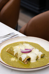 Enchiladas suizas ba&ntilde;adas en salsa verde cremosa, gratinadas y con cebolla morada 