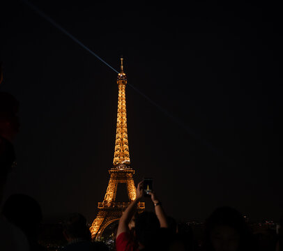 Paris, France: Eiffel Tower view at night with tourists taking pictures
