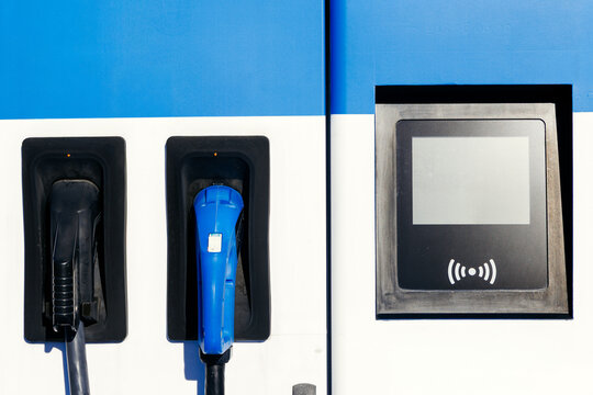 Electric vehicle charging station with two charging connectors and a digital display, showcasing modern technology and sustainable energy solutions for eco-friendly transportation - Powered by Adobe