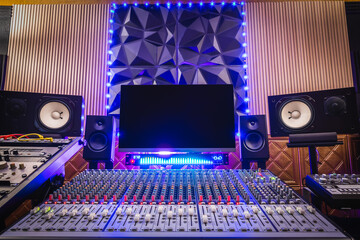home recording studio. mixing console, studio monitors, desktop computer and professional audio equipment with modern sound diffuser wall design.