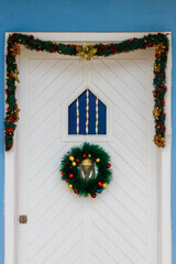 Festive Christmas Door Decor With Wreath and Garland on Bright Blue Wall
