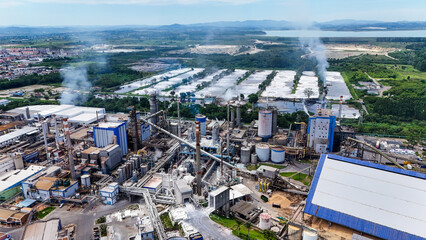 Fototapeta premium Imagem aérea de fábrica de papel e celulose com infraestrutura industrial pesada, mostrando chaminés, caldeiras e os efeitos ambientais da produção.