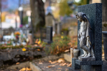 Statue of an angel in a cemetery at evening with a burning candle.Memory of the deceased. Expression of love