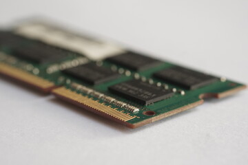 A selective focus of side-profile shot of a laptop RAM module on white. Focuses on the thickness of the PCB and the soldering details of the connector pins.