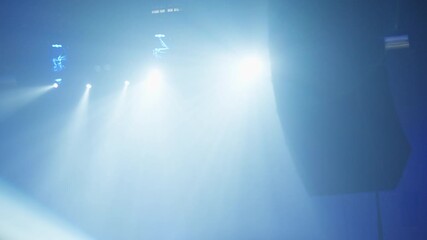 Intense blue stage lights projecting wide beams across dark venue interior emphasizing scale of live performance and immersive concert experience