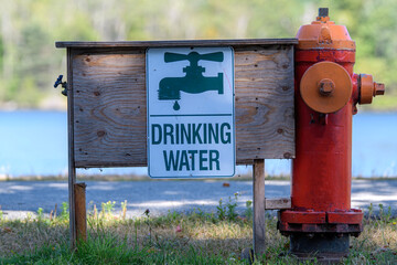 A fire hydrant in a park configured to provide drinking water as well as fight fires. A sign shows a tap and says "DRINKING WATER". Spout on left.