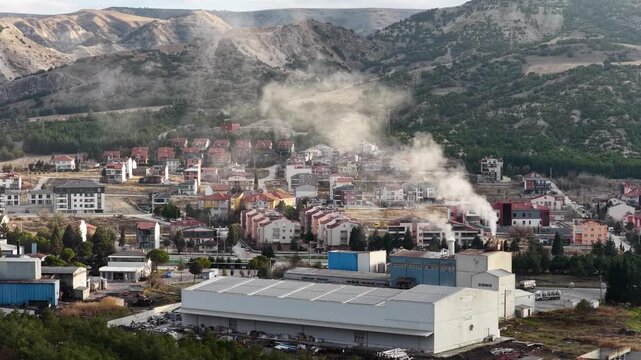 Aerial view of the industrial facility and the residential area immediately behind it. A drone shot of the mountain landscape where city and industrial life intertwine.