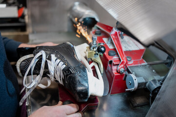 Professional hockey skate sharpening machine grinding blade with visible sparks, showing automated precision equipment used by elite teams for skate maintenance