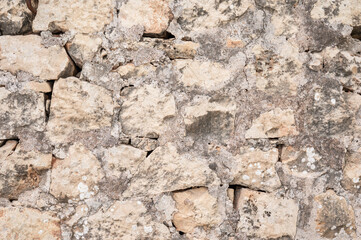 Obraz premium Strongly weathered limestone wall with rough texture and dirty brown ochre tones, suitable as an abstract background reflecting traditional Maltese building materials Iz-Zeytun, Malta, 10 DEC 2025.