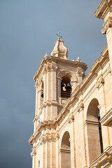 Fototapeta premium Architectural detail of Saint Catherine Church, showcasing intricate stonework and traditional Maltese religious architecture Iz-Zeytun, Malta, 10 DEC 2025.