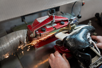 Professional hockey equipment manager sharpening ice skate blades on automatic machine with visible sparks, demonstrating elite team equipment maintenance and service workflow