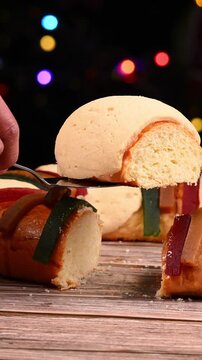Close-up of a Rosca de Reyes (Three Kings' Bread) being cut on a wooden table. January 6th in Mexico