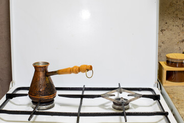 Coffee pot or cezve resting on a gas stove in a kitchen, ready for brewing morning coffee. Real photo.