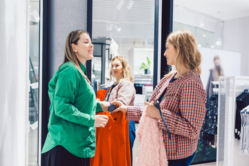 Two female friends are choosing clothes in store. High quality photo