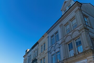 Low-angle view of ornate, pastel-colored townhouses under a clear blue sky, bathed in bright sunlight, creating a serene, architectural composition in Caernarfon - Gwynedd - Wales - UK