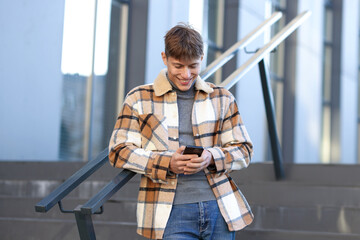 Smiling man in shirt with smartphone near railings outdoors