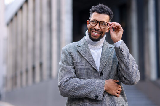 Smiling man in glasses and suit on city street. Space for text