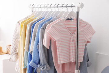 Obraz premium Different stylish clothes hanging on rack near white wall indoors, closeup