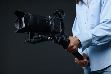 Videographer using gimbal stabilizer with camera on black background, closeup © New Africa