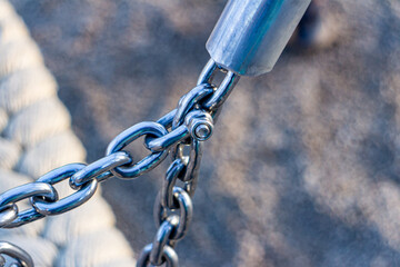Naklejka premium Close-up of metal chain links connected to a steel fitting. Industrial fastening detail highlighting strength,