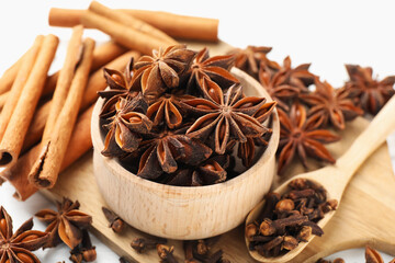 Mulled wine spices. Anise stars in bowl, cinnamon sticks and cloves on white table, closeup