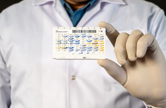 Medical professional holding VITEK diagnostic card for automated microbial