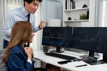 Successful smiling Asian business partners raising fist up together in profitable project job in...